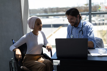 Disabled mixed-race woman and Caucasian male doctor interacting with each other