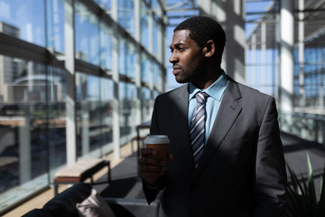 African-American of businessman with coffee cup looking away in office