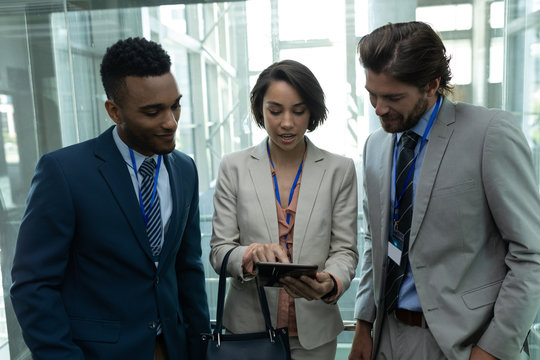 Multi-ethnic business people discussing over digital tablet in office elevator