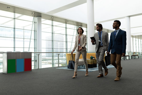 Multi-ethnic business people interacting with each other while walking on office floor