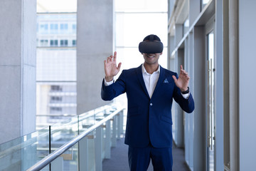 Young mixed-race businessman using virtual reality headset in modern office