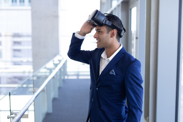 Mixed-race businessman using virtual reality headset standing in modern office