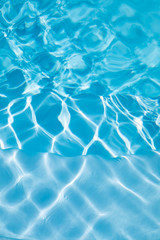 background stairs inside swimming pool with blue transparent water vibrating with ripples, vertical