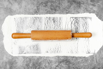 Rolling pin and white flour on a gray background. Bake menu, recipe, homemade pastry concept. Free space for text . Flat lay, top view, copy space for your text.
