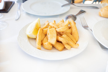 white circular plate with sepia or squid breaded and fried, typical food of Andalusia in Spain Europe on white tablecloth ready to serve