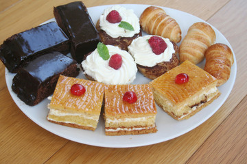 Different pastry with chocolat and cream on a white plate on wooden table. Sweet food