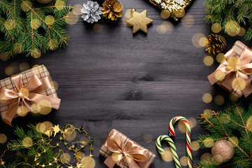 Christmas frame flat lay with pine, presents, golden elements, candy canes, confetti. Christmas template on dark wood