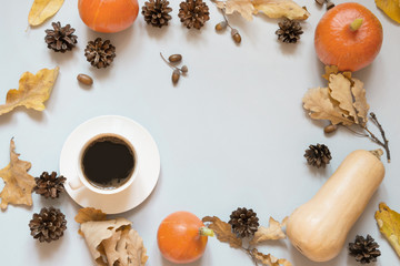 Fall still life, black coffee, dry leaves and pumpkin on grey. Top view and copy space.