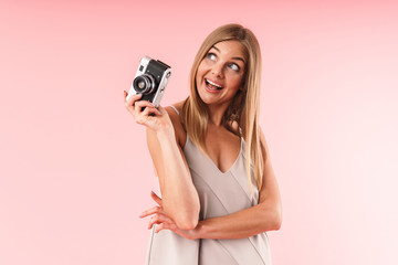 Image of attractive blond woman wearing dress smiling while holding retro camera