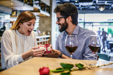 Birthday present for a girlfriend. Romantic couple sitting in the cafe and drinking red wine. Dating, love, relationships