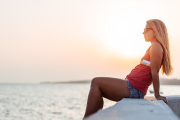 Fototapeta na wymiar Young woman enjoying sunset by the sea
