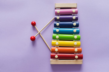 A toy wooden colorful xylophone on purple background with copy space. Children's toy and musical instrument. Music and childhood concept.