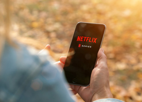 AACHEN, GERMANY - 31. August 2019 : Netflix app on Apple iPhone. Young man is browsing the movie video library what to watch.
