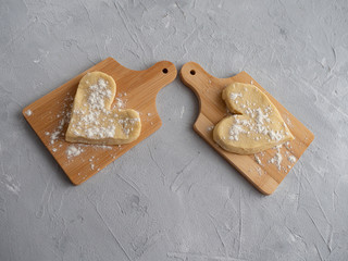 Two heart-shaped muffin blanks on small wooden planks against a gray concrete background.