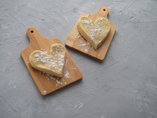 Two heart-shaped muffin blanks on small wooden planks against a gray concrete background.