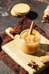 Spicy pear jam in glass jar, crackers, spices (cinnamon and anise) and thyme. Brown stone background. Rustic style.
