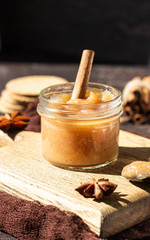 Spicy pear jam in glass jar, crackers, spices (cinnamon and anise) and thyme. Brown stone background. Rustic style.