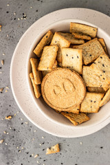 Thin crispy wholegrain crackers with seeds on grey concrete background. 