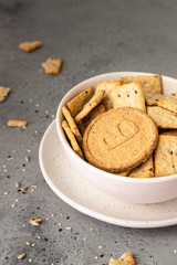 Thin crispy wholegrain crackers with seeds on grey concrete background. 