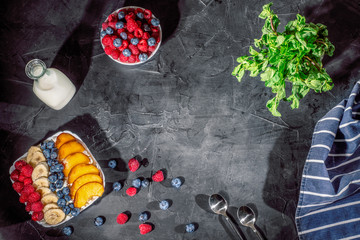 Cottage cheese with fresh raspberries, blueberries and peaches in a bowl for healthy breakfast on dark background