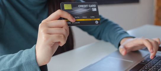 panoramic banner. young woman entering security code with laptop computer and paying credit card on desk at home office, internet technology, electronic online booking, payment and shopping concept