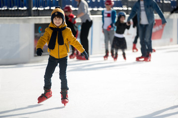 Happy boy with hat and jacket, skating during the day, having fun .