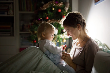 Young beautiful mother, breastfeeding her newborn baby boy at night, dim light. Mom breastfeeding toddler