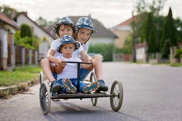 Happy children, boys, riding old retro car with four wheels