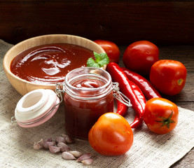 Tomato red sauce in wood bowl and glass bottle with copy space for food issue, recipe or cooking.