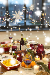 christmas dinner and eating concept - food and drinks on table at home over snow