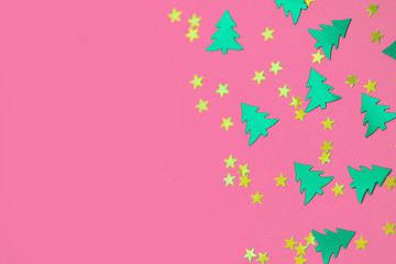 green christmas trees and gold stars confetti sparse on pink background