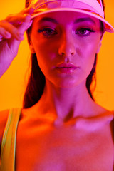 Image closeup of fashionable brunette woman wearing sun visor cap and sportswear posing at camera