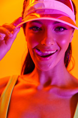 Image closeup of flirting brunette woman wearing sun visor cap and sportswear smiling at camera