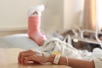 The intravenous fluid on a woman patient hand after surgery leg in the hospital.