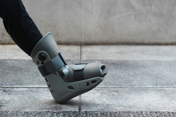 A Asian girl is wearing a ankle support boot after surgery.