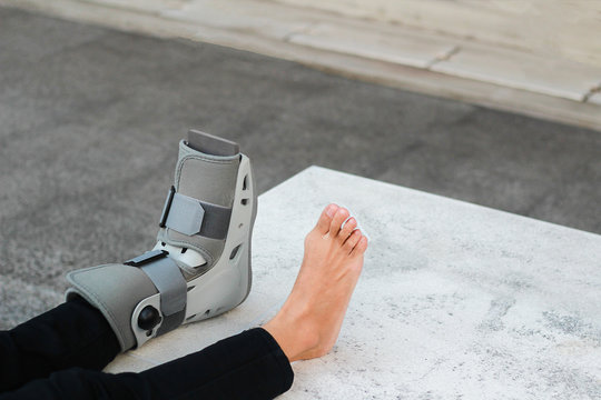A Asian girl is wearing a ankle support boot after surgery.