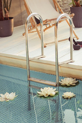 Swimming pool with stair and wooden deck at hotel.