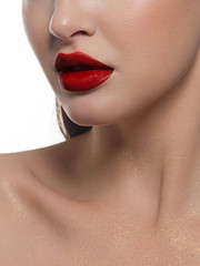 Fototapeta premium Cosmetics, makeup and trends. Bright lip gloss and lipstick on lips. Closeup of beautiful female mouth with red lip makeup. Beautiful part of female face. Perfect clean skin in red light