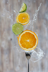 Citrus on a fork in water splashes on a gray background