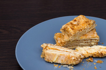 Layered cake. Cake Napoleon from puff pastry with sour cream. Macro photo of a dessert. puff cake with butter cream. piece of cake on a gray plate.