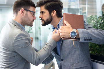 Business conflict between two business men in formal-wear in office. Boss and employee with...