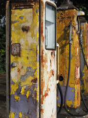 Old yellow petrol pumps with flaking paint.