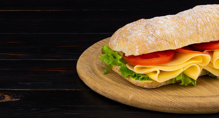 Ciabatta sandwich with lettuce , prosciutto and  cheese on wooden board with copy space
