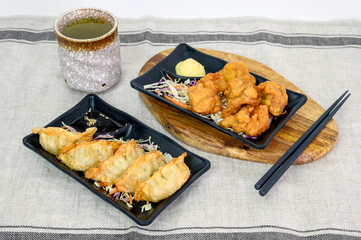 Karaage chicken deep fried with Gyoza dumplings and hot tea on cloth
