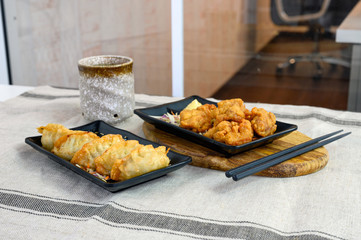 Karaage chicken deep fried with Gyoza dumplings and hot tea on cloth