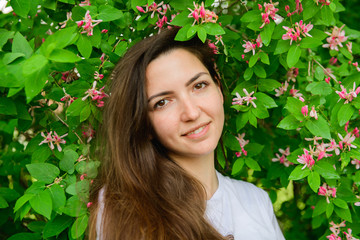 Young beautiful girl near the flowers. photon green and flowers. Portrait of young beautiful girl...