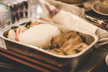 airline inflight economy class meal served on a tray with steamed rice, soy sauce chicken and stir fried vegetables