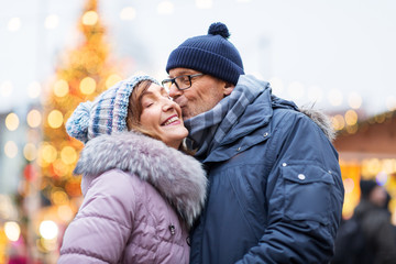 love, winter holidays and people concept - happy senior couple kissing at christmas market