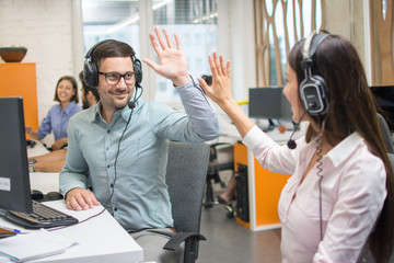 Customer service support operators giving high five to each other and celebrating successful...