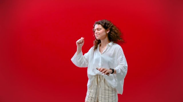 Girl dancing with an iPhone 11pro in hand on a red background